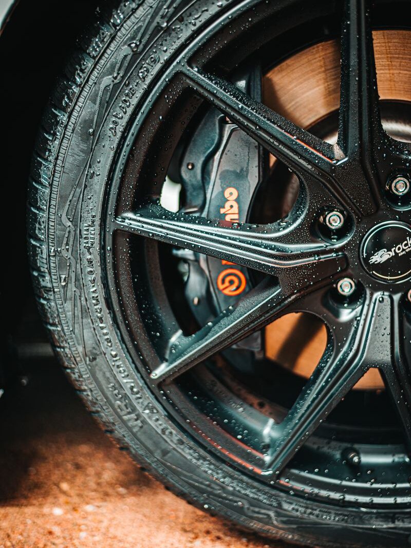 Detailed photo of a black alloy wheel with visible water droplets and a prominent Brembo brake caliper.